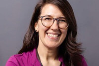 Dr. Veronika Sunko mit dunklem Haar und Brille, in pinkem Oberteil.